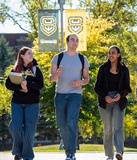 Three students discussing Academic Microcredentials while walking on a campus path.