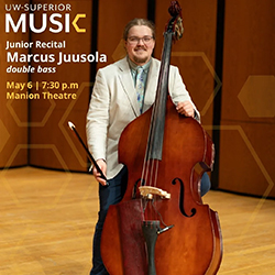 A man in a suit stands on stage holding a double bass next to a recital announcement sign.