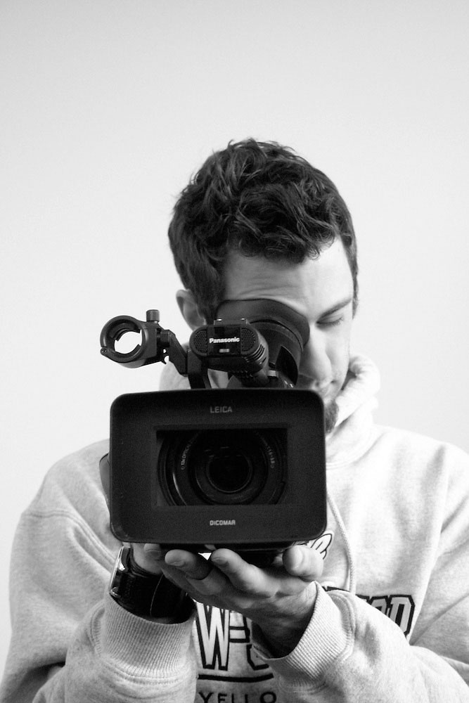 Person holding a video camera, facing forward—a scene from communication and media arts.