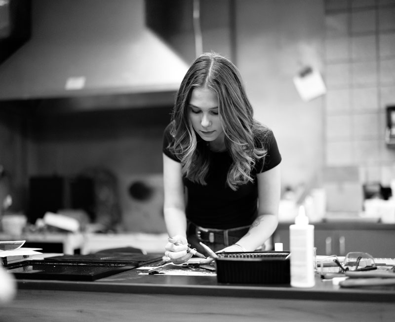 Woman engaged in art therapy, crafting items with focus at a worktable in a workshop.