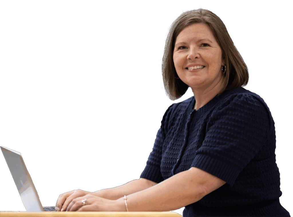 Jamie White-Farnham sits at a desk and smiles while typing on a laptop at the University of Wisconsin-Superior.
