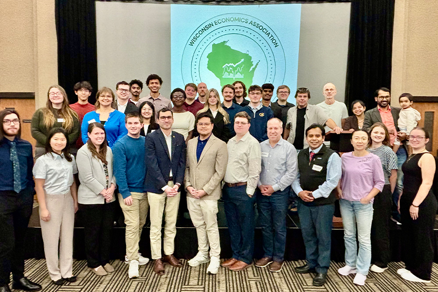 A large group of people posing for a photo in front of a Wisconsin Economics Association banner.