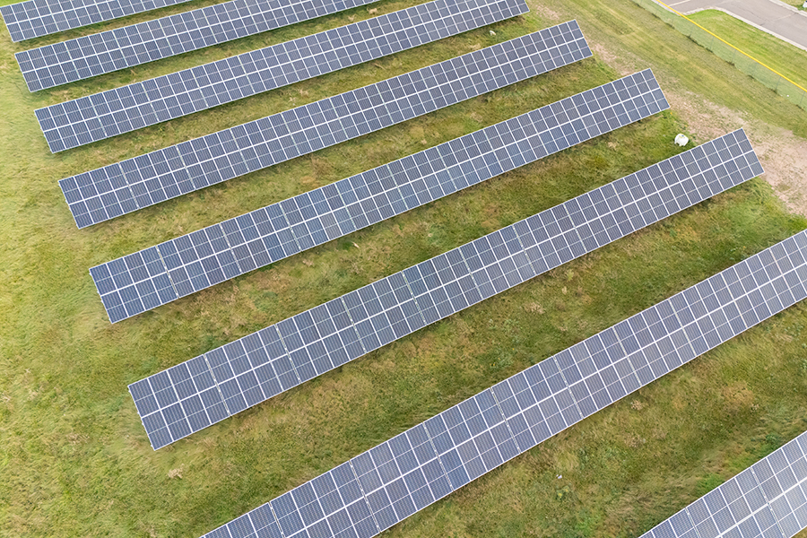Rows of solar panels installed on a grassy field, viewed from above.