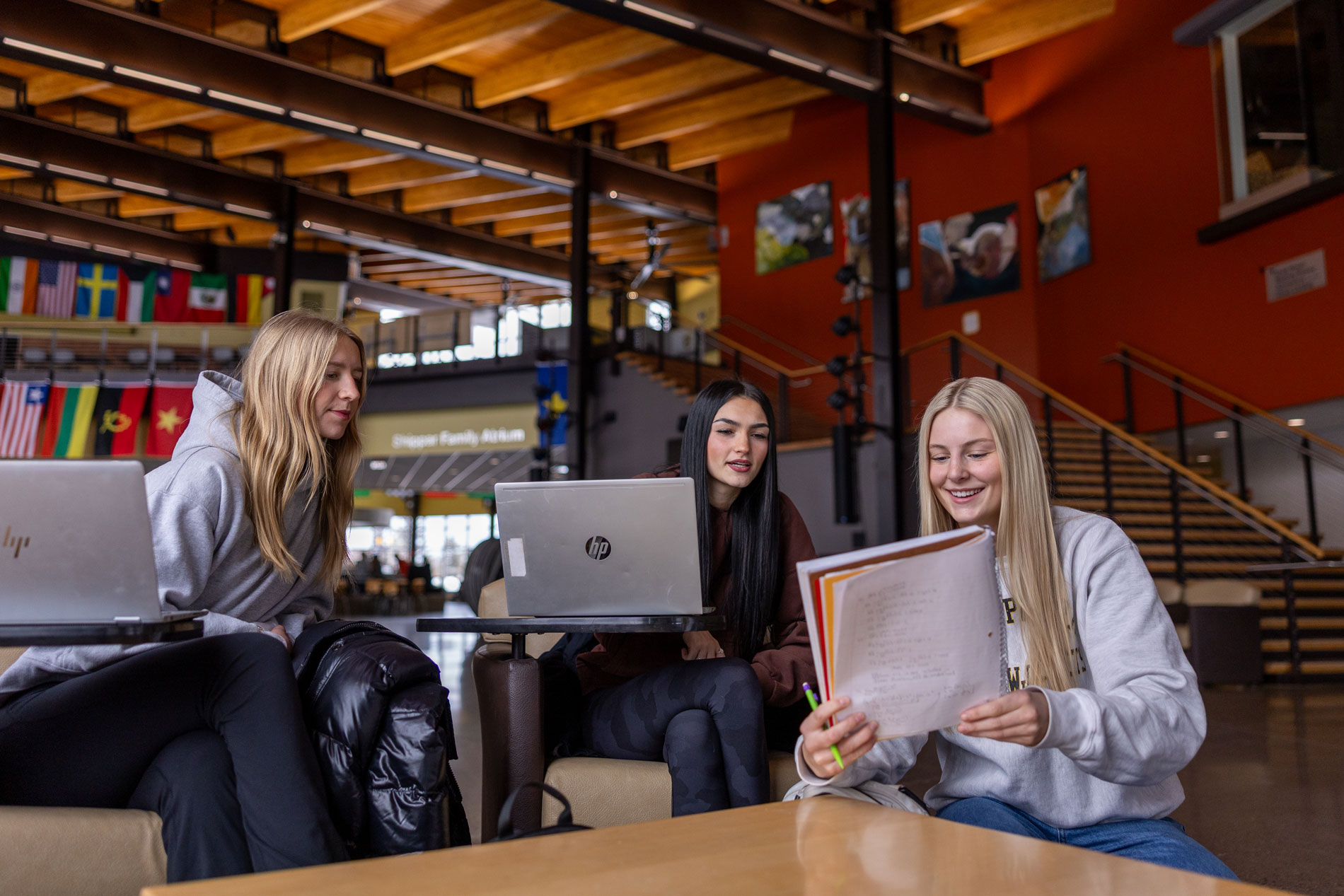 Three young women study Computer Science Education together in a modern, brightly lit common area.