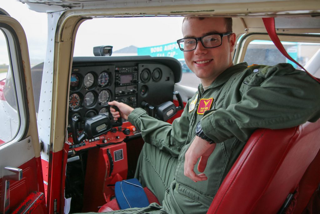 Male ROTC student smiling and sitting inside a small aircraft