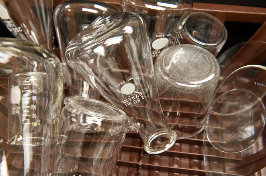 A close-up view of various clean laboratory glassware, including beakers and flasks, placed upside down on a drying rack—ideal for hands-on science education activities.