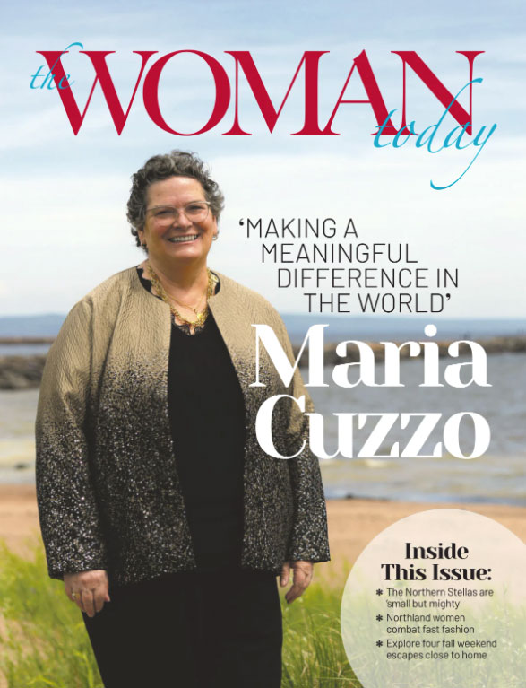 Maria Cuzzo stands outdoors near water, featured in the October 2026 issue of The Woman Today.